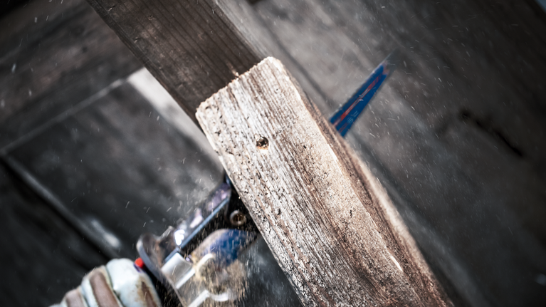 EXPERT ‘Multi Material’ 956 XHM Reciprocating Saw Blade 1-pc Person wearing safety equipment cuts a wooden plank with a reciprocating saw.