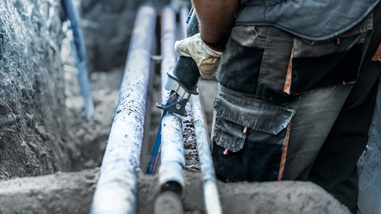 EXPERT ‘Thick Tough Metal’ S 555 CHC Reciprocating Saw Blade 1-pc Person wearing safety equipment cuts a pipe with a power saw in a trench.