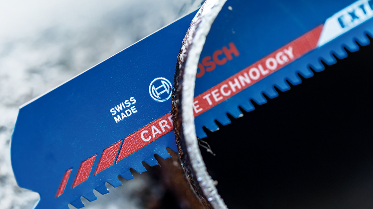 EXPERT ‘Thick Tough Metal’ S 955 CHC Reciprocating Saw Blade 1-pc Close-up of a blue saw blade with carbide teeth cutting through a metal pipe.