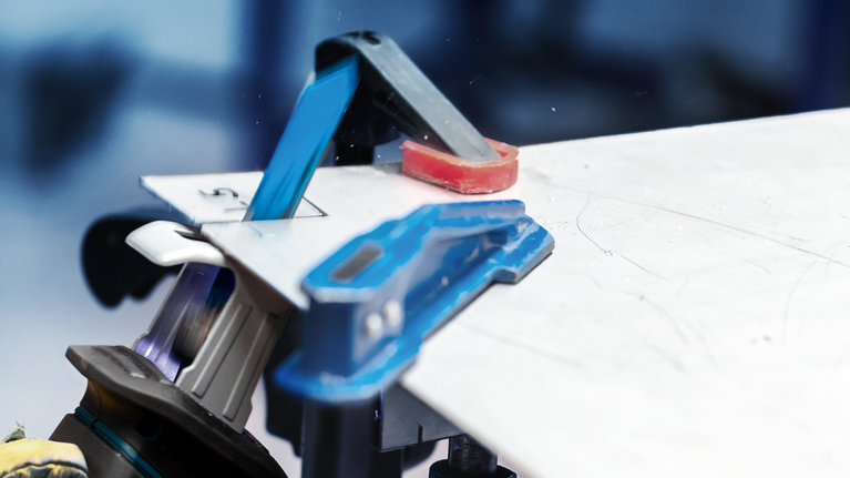 EXPERT ‘Thin Tough Metal’ S 522 EHM Reciprocating Saw Blade 1-pc A person wearing safety equipment cuts a sheet material with a power tool on a workbench.