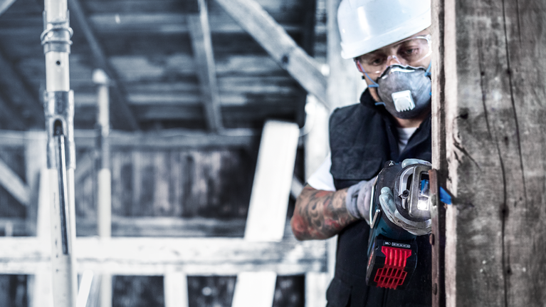 EXPERT Wood with Metal Demolition S967XHM Reciprocating Saw Blade 1-pc A person wearing safety equipment uses a cordless angle grinder to cut through wood.