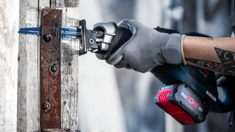 EXPERT Wood with Metal Demolition S967XHM Reciprocating Saw Blade 1-pc Person wearing safety equipment uses a reciprocating saw to cut a metal plate.