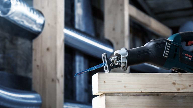 EXPERT Wood with Metal S715LHM Reciprocating Saw Blade 1-pc Reciprocating saw cutting through a stack of wooden beams in a construction setting.