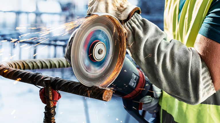 EXPERT Diamond Metal Wheel Cutting Disc 180 x 22.23 mm A person wearing safety equipment cuts a metal rod with a power tool, sparks flying.