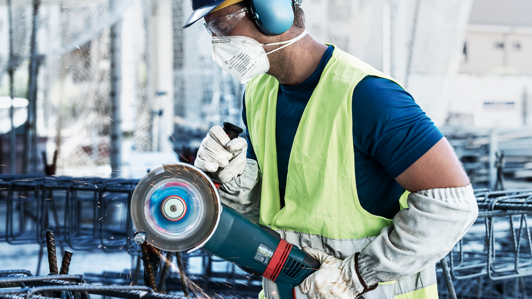 EXPERT Diamond Metal Wheel Cutting Disc 180 x 22.23 mm A person wearing safety equipment grinds metal rebar with a power tool, creating sparks.