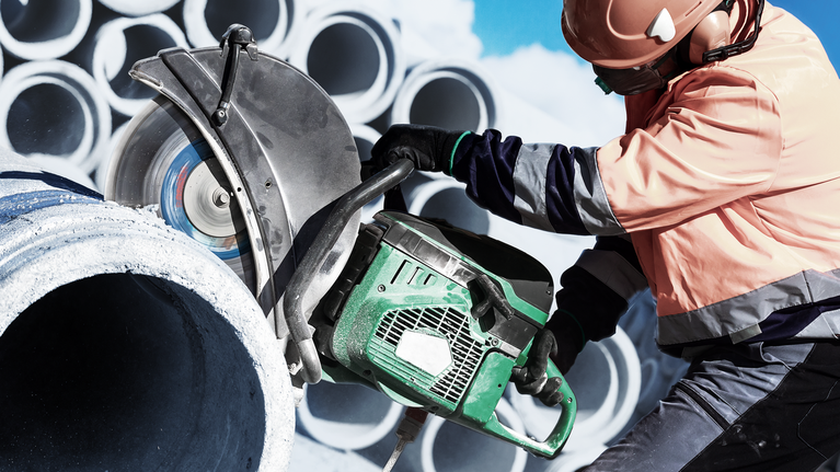 EXPERT MultiMaterial Diamond Cutting Disc 350 x 20/25.40 x 3.3 x 15 mm A person wearing safety equipment cuts a concrete pipe with a large power saw.