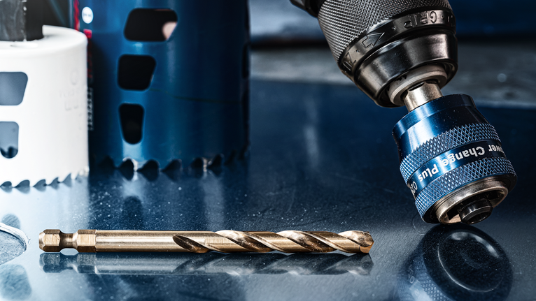 EXPERT Power Change Plus Pilot Drill Bit HSS-Co 7.15 x 105 mm A close-up of a drill chuck and a drill bit on a reflective metal surface.