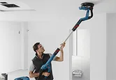 Man sanding ceiling drywall