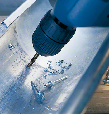 Double-ended drill bit HSS-G Cordless drill creating a hole in a metal channel near metal rivets.