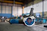 Angle grinder with X-LOCK system resting on a workbench in an industrial workshop.