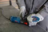 A person wearing safety equipment secures a grinding disc onto an angle grinder.