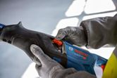 Person wearing safety equipment adjusts the speed setting on a reciprocating saw.