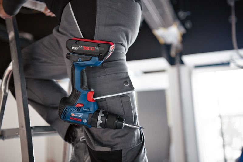 GSB 18V-55 A person wearing safety equipment stands on a ladder with a cordless combi drill in their pocket.