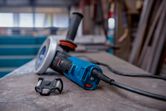 Electric angle grinder resting on a workbench beside a small dust filter.
