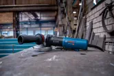 Angle grinder resting on a metal worktable in an industrial workshop.