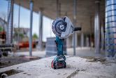 Cordless angle grinder with a diamond blade standing upright on a concrete surface.