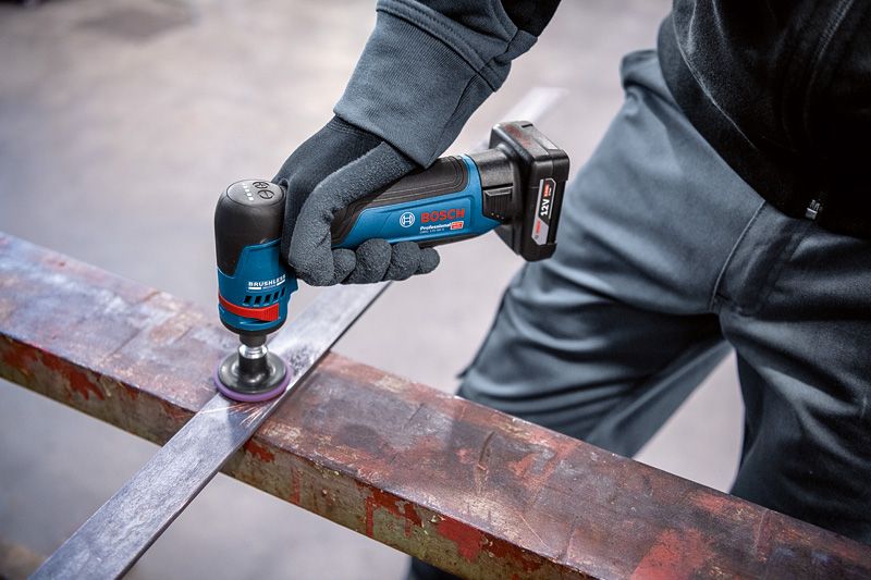 A person wearing safety equipment uses a rotary grinder to polish a metal beam.