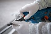 Person wearing safety equipment adjusts a cordless concrete nailer.