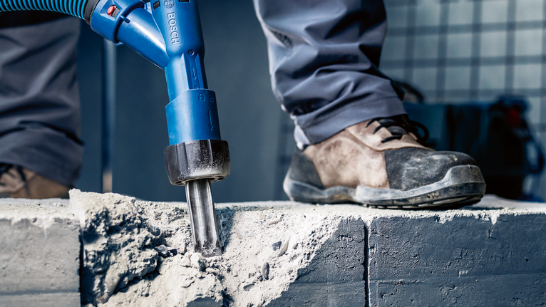 EXPERT SDS Clean max Pointed Chisel Adapter 400 mm Person wearing safety equipment breaks concrete with a power tool.