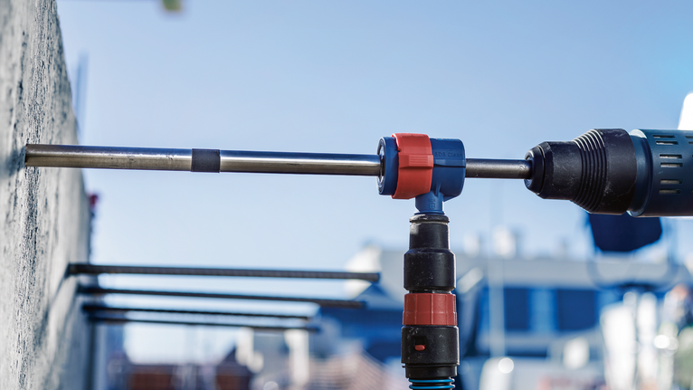 EXPERT SDS Clean plus-8X Hammer Drill Bit 20 x 400 x 550 Rotary hammer drilling a hole into a concrete wall outdoors.