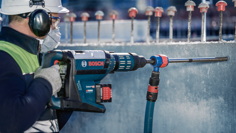 EXPERT SDS Clean plus-8X Hammer Drill Bit 20 x 400 x 550 A person wearing safety equipment drills into concrete with a rotary hammer.