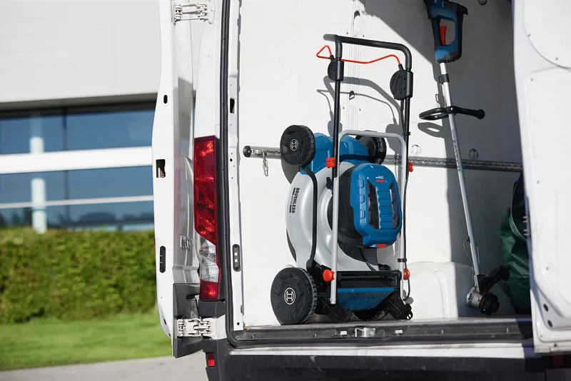 Folded cordless lawnmower and trimmer stored in the back of a white work van.