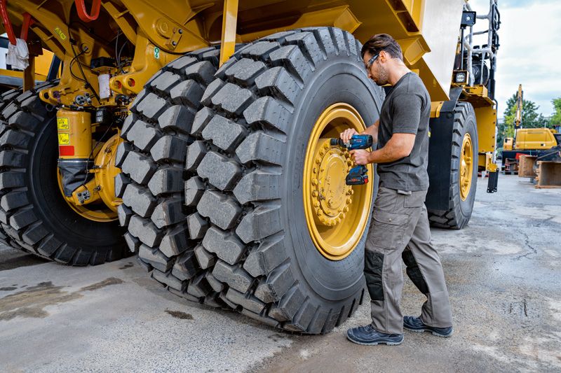 GDS 18V-1600 HC A person wearing safety equipment uses an impact wrench on a large construction vehicle tire.