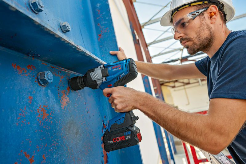 GDS 18V-1600 HC A person wearing safety equipment uses a cordless impact wrench on a large metal beam.