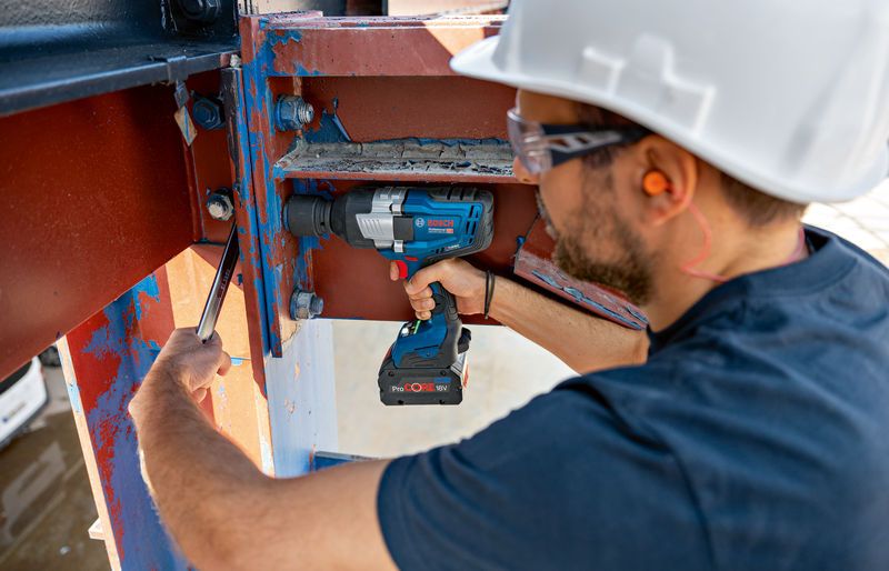 GDS 18V-1600 HC A person wearing safety equipment uses a cordless impact wrench on a steel beam.