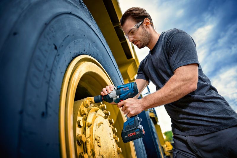GDS 18V-1600 HC A person wearing safety equipment uses an impact wrench on a large vehicle wheel.