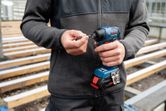A person inserts a drill bit into a cordless screwdriver at a construction site.