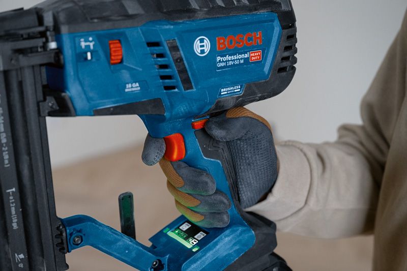 Person wearing safety equipment operates a cordless brad nailer.