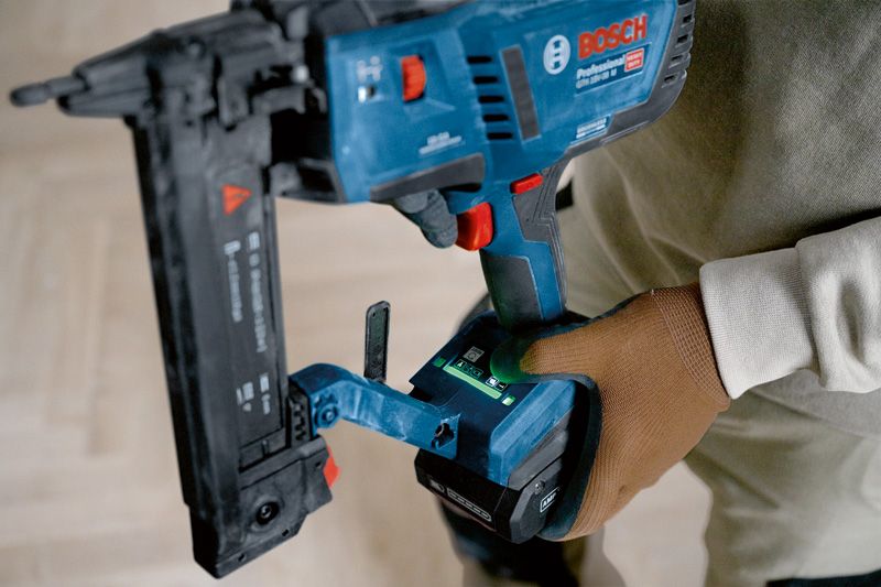 Person wearing safety equipment using a cordless narrow crown stapler.