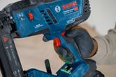 A person wearing safety equipment operates a cordless wood stapler.