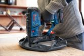 Person wearing safety equipment uses a cordless wood stapler to fasten upholstery.