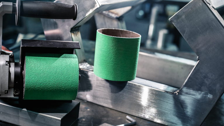 PRO Y580 Sanding Belt, 100 x 285 mm, 90 mm, G40, 5 pcs Green sanding drum tool and sanding sleeve placed on a metal workbench.
