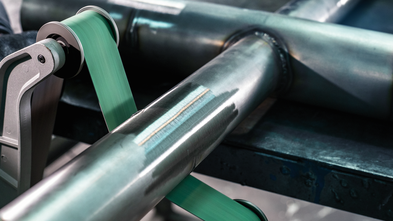 PRO Y580 Sanding Belt, 100 x 285 mm, 90 mm, G40, 5 pcs Grinding tool polishing a metal pipe on a workbench.