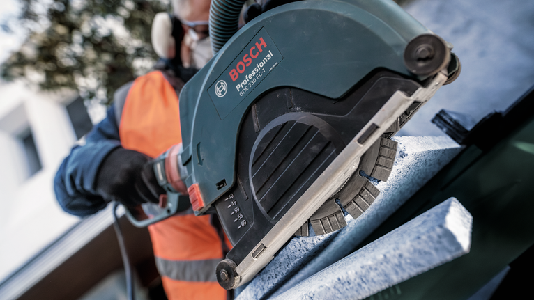 PRO Stone Diamond Disc, 180 x 22.23 mm A person wearing safety equipment uses a power saw to cut a stone slab.