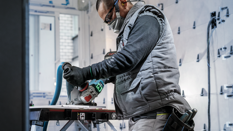 PRO Ceramic X-Lock Diamond Disc, 125 x 22.23 mm, 22.23 mm Person wearing safety equipment uses a power tool to cut material on a workbench.