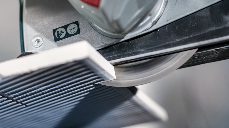 PRO Ceramic X-Lock Diamond Disc, 125 x 22.23 mm, 22.23 mm Tile cutter slicing a ceramic tile in a workshop.