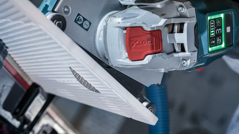 PRO Ceramic X-Lock Diamond Disc, 125 x 22.23 mm, 22.23 mm Angle grinder cuts through a ceramic tile along a marked line.