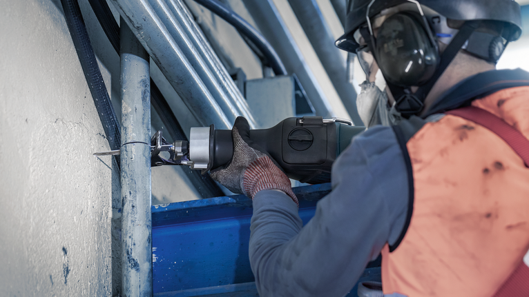PRO Thick Metal Demolition S930CF Blade, 1.6 x 22 x 150 mm, 5 pcs Person wearing safety equipment cuts through a metal pipe with a reciprocating saw.