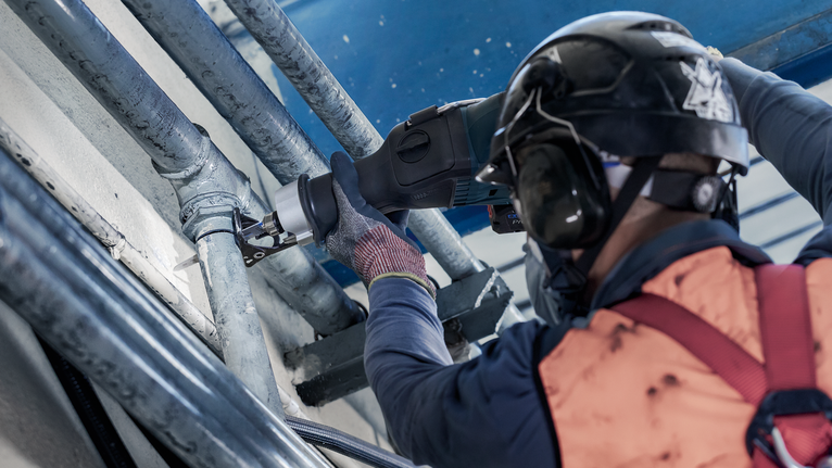 PRO Thick Metal Demolition S930CF Blade, 1.6 x 22 x 150 mm, 5 pcs Person wearing safety equipment cuts a metal pipe with a reciprocating saw.