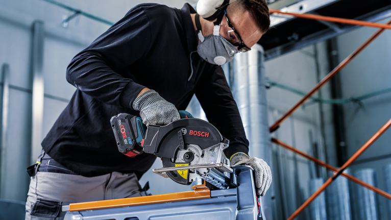 PRO Steel cordless Circular Saw Blade, 136 x 1.6 x 20 mm A person wearing safety equipment uses a circular saw to cut metal.