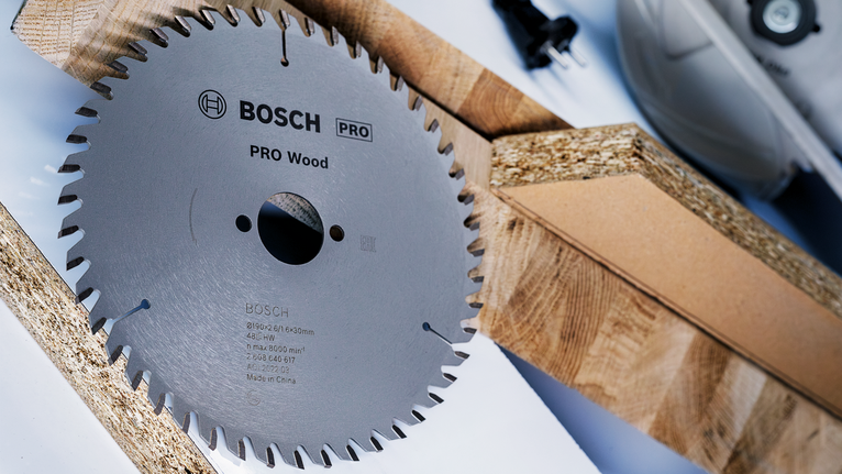 PRO Wood Circular Saw Blade, 85 x 1.1 x 15 mm Circular saw blade placed beside wooden planks on a work surface.