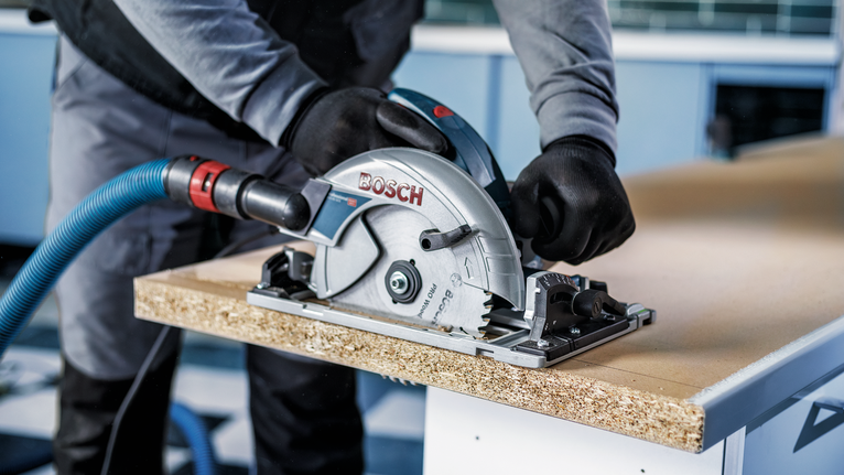 PRO Wood Circular Saw Blade, 85 x 1.1 x 15 mm Person wearing safety equipment cuts wood panel with a circular saw.