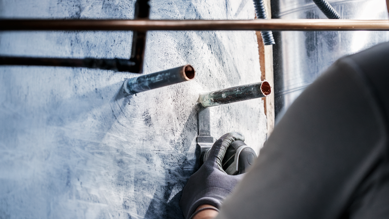 PRO AIZ 32 AIB Plunge Cut Blade, 32 x 50 mm, 5 pcs Person wearing safety equipment uses a power tool to cut into a wall around metal pipes.