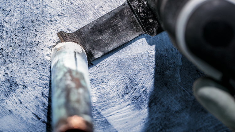 PRO AIZ 32 AIB Plunge Cut Blade, 32 x 50 mm, 5 pcs Person wearing safety equipment cuts through a metal pipe with a reciprocating saw.