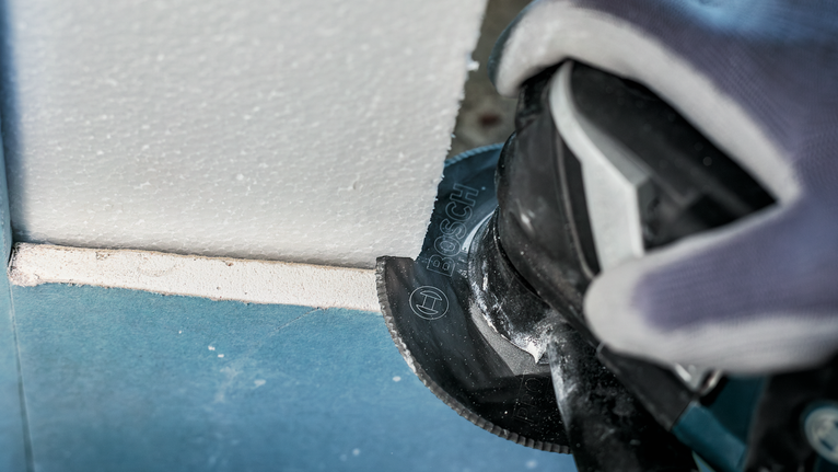 PRO ACZ 100 SWB Multitool Blade, 100 mm Person wearing safety equipment cuts plasterboard with a power tool.