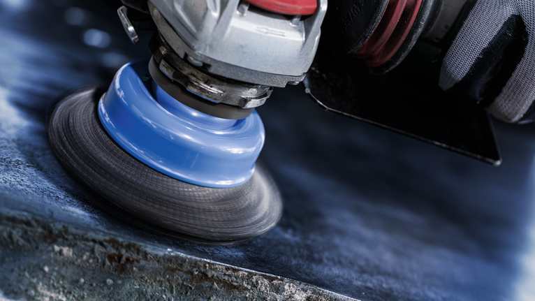 PRO Metal heavy X-Lock Cup Brush, 75 x 0.35 mm Person wearing safety equipment polishes a metal surface with a power tool.